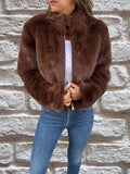 Women's brown faux fur bomber jacket with high collar and zip front worn with jeans