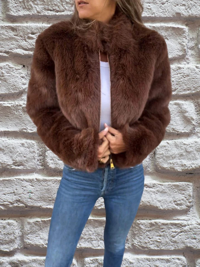 Women's brown faux fur bomber jacket with high collar and zip front worn with jeans