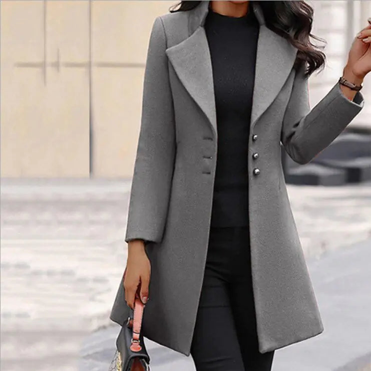 Close-up view of women's long tailored coat showing structured fabric, notch lapels, and decorative button accents.