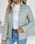 Women's quilted puffer jacket in mint green with stand collar and horizontal quilting, worn over white ribbed turtleneck