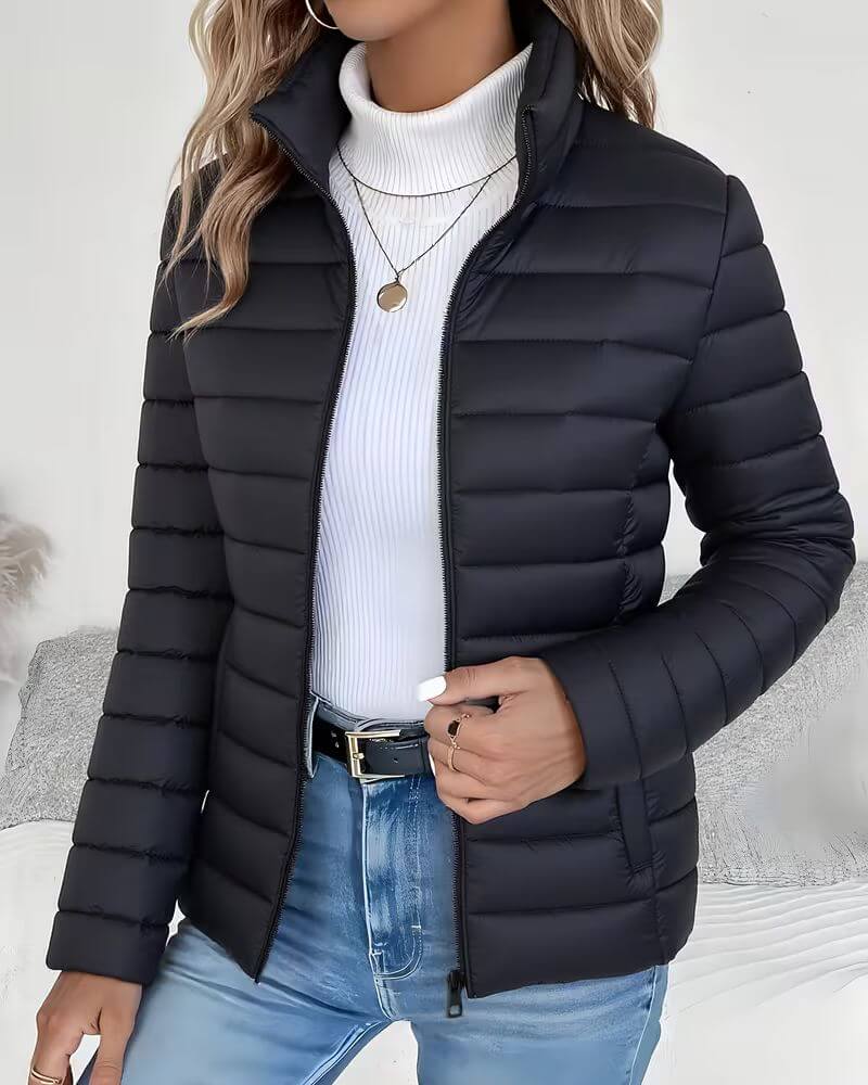 Fitted women's puffer jacket with cropped length and full zip closure, styled with blue denim jeans