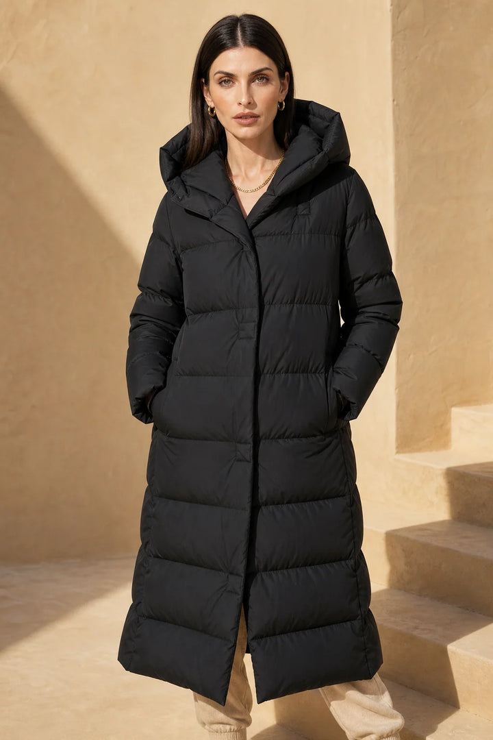 Side profile of women's long puffer parka displaying full-length silhouette and quilted panel construction