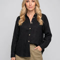 Women's relaxed linen shirt in black with classic collar and button front detail worn with beige trousers
