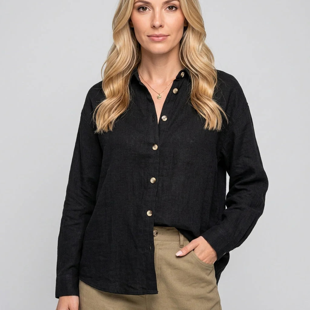 Women's relaxed linen shirt in black with classic collar and button front detail worn with beige trousers