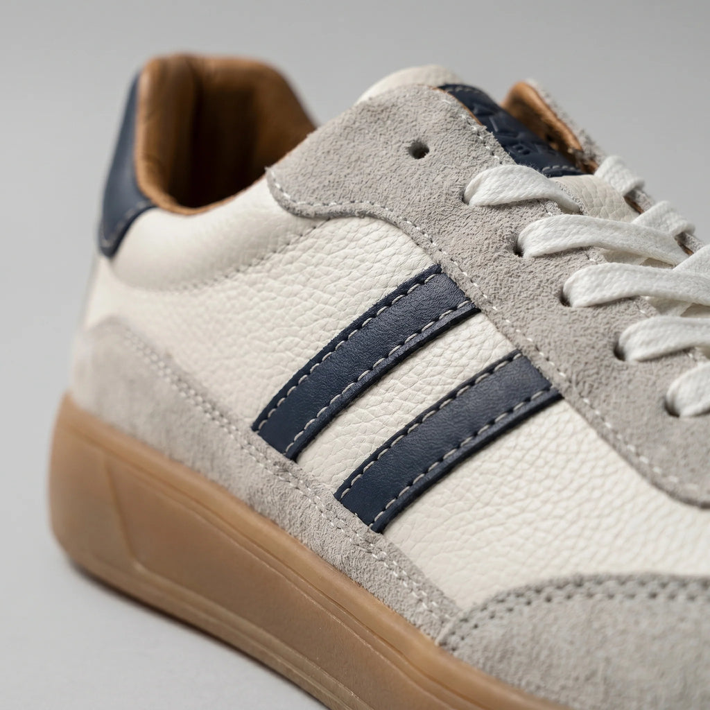 Close-up of men's retro trainers featuring contrasting navy and cream design