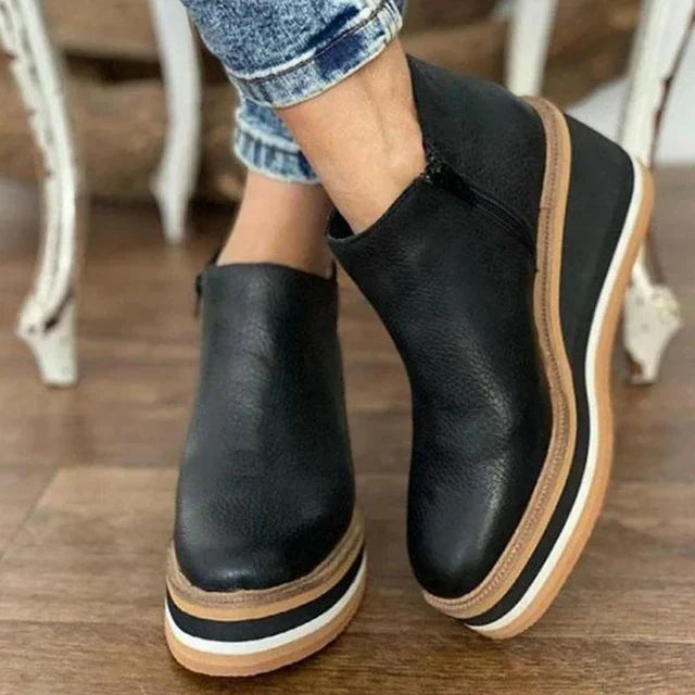 Close-up of women's ankle boots showing smooth finish and contrast striped sole detailing