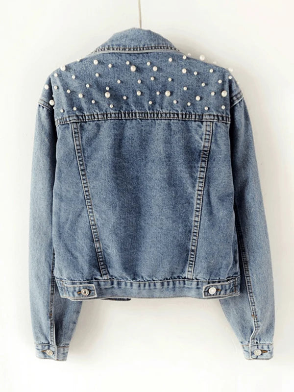 Close-up view of pearl-embellished cropped denim jacket showing relaxed fit and button-front closure with chest pockets