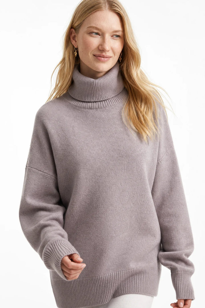Woman styled in the white oversized turtleneck jumper paired with tailored trousers for casual elegance