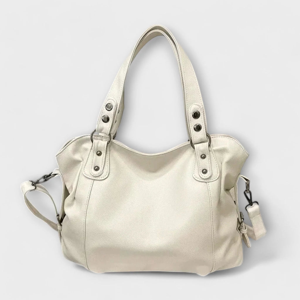 Cream hobo shoulder bag with studded handles and detachable crossbody strap on neutral background