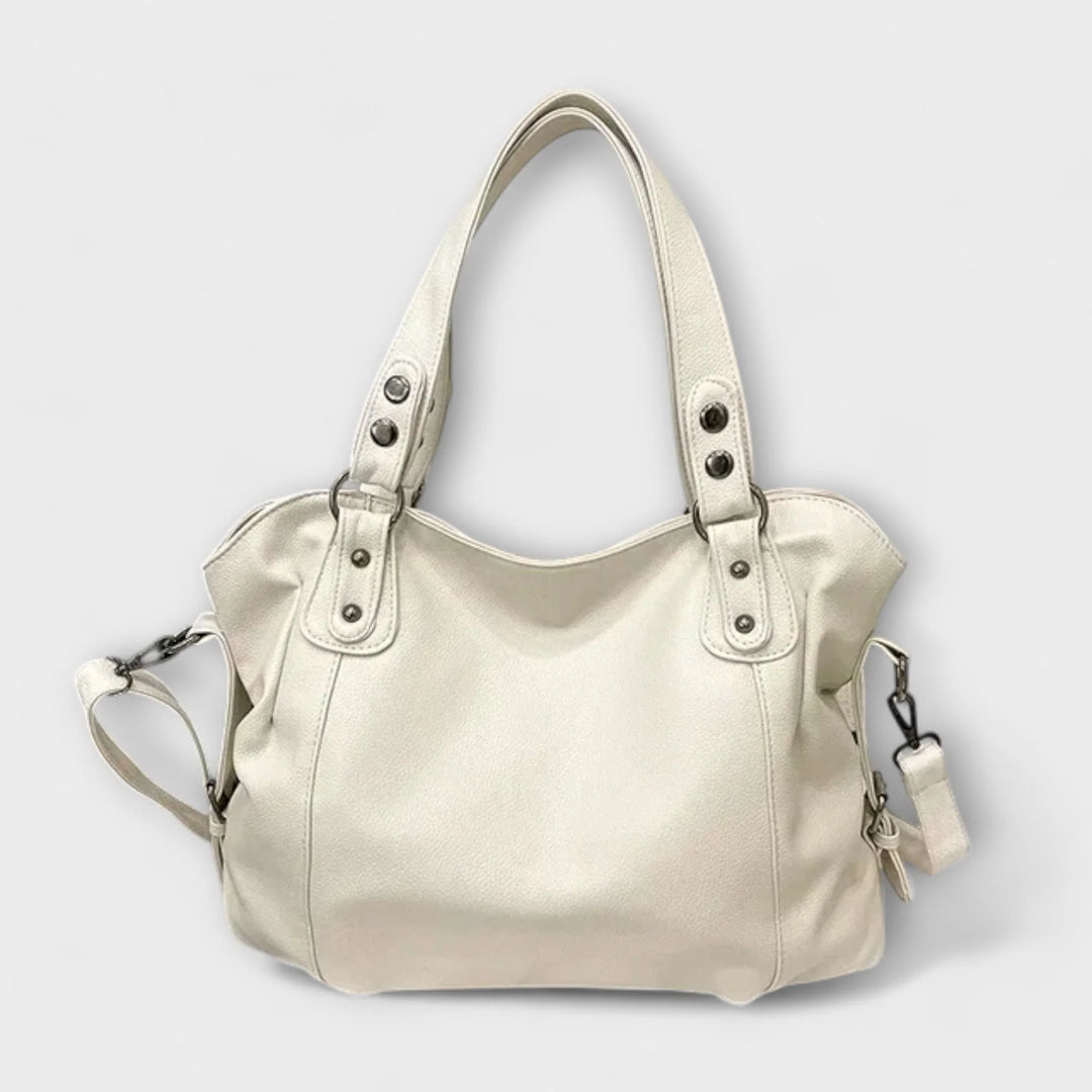 Cream hobo shoulder bag with studded handles and detachable crossbody strap on neutral background