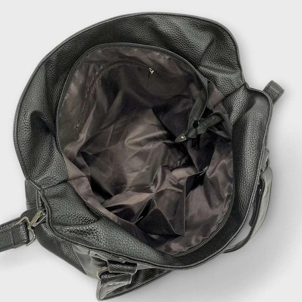 Back view of hobo bag displaying smooth structured material and side zip pocket
