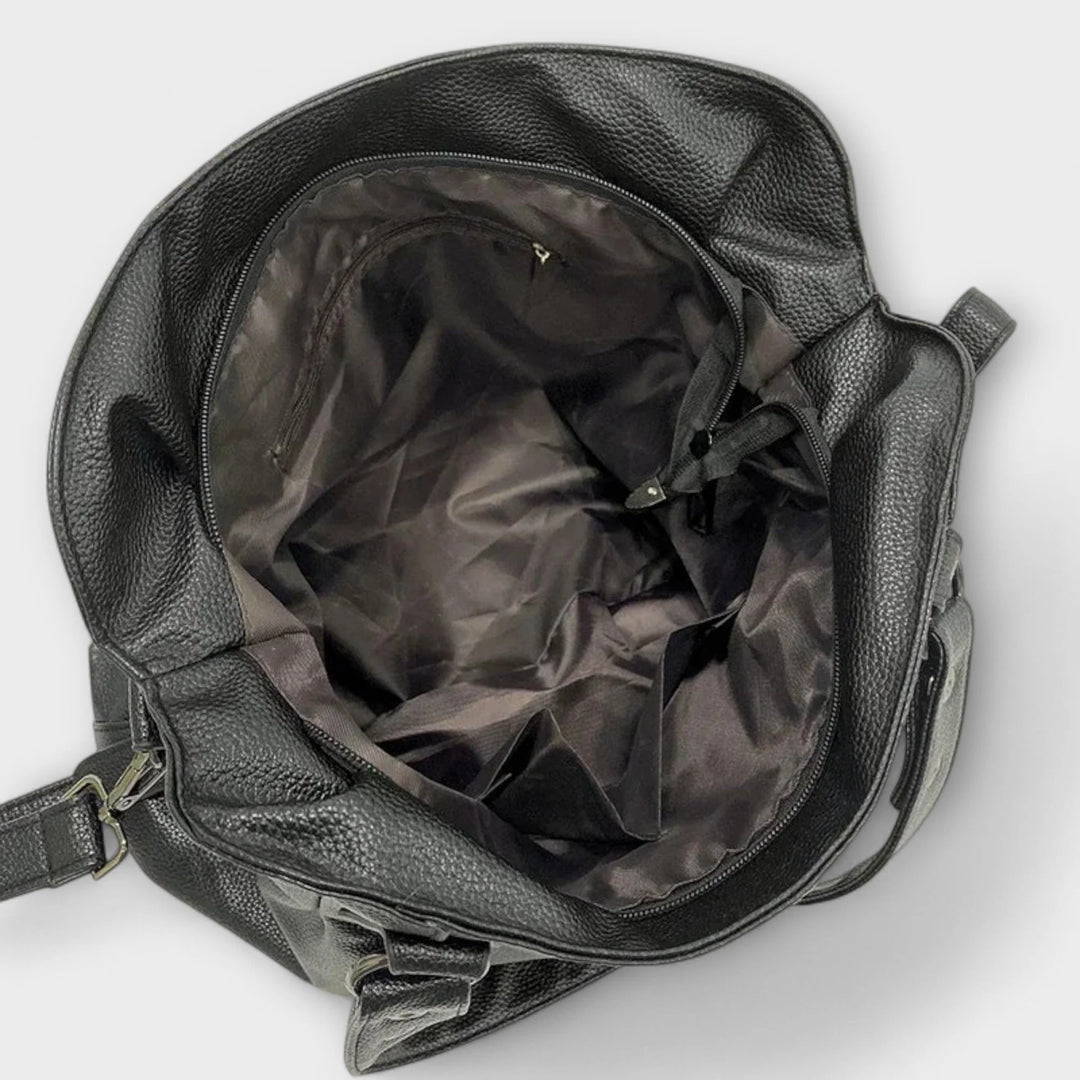 Back view of hobo bag displaying smooth structured material and side zip pocket
