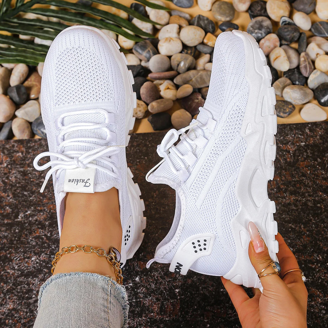 Women's white mesh trainers with wide toe box and lace-up closure on pebbled surface