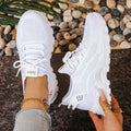 Women's white mesh trainers with wide toe box and lace-up closure on pebbled surface