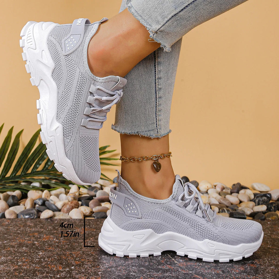 Close-up of women's white mesh trainers showing breathable knit upper and chunky sole