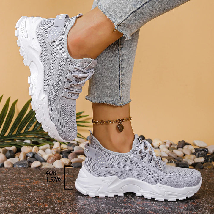 Close-up of women's white mesh trainers showing breathable knit upper and chunky sole