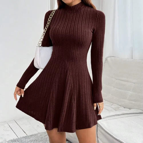 Women's ribbed knit dress in brown with mock neck and flared hem, styled with white handbag