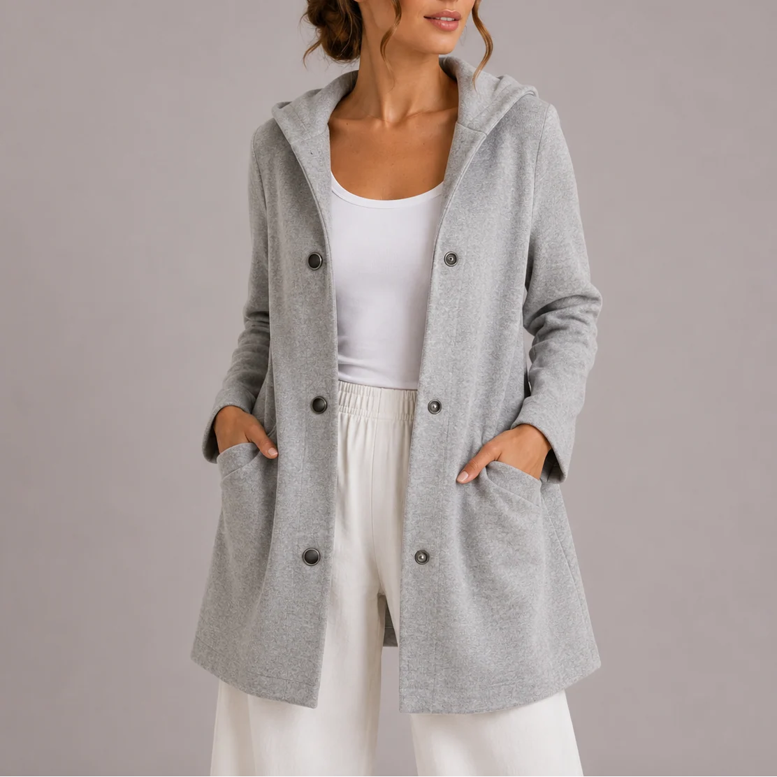 Close-up of hooded double-breasted jacket showing button closure and structured fabric drape