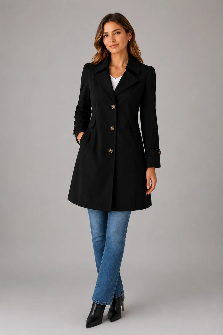 Women's beige trench coat styled with jeans showing knee-length silhouette