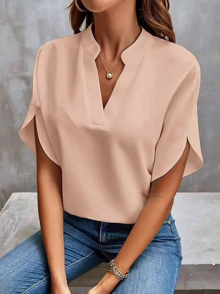 Women's blouse in office setting paired with tailored trousers and accessories