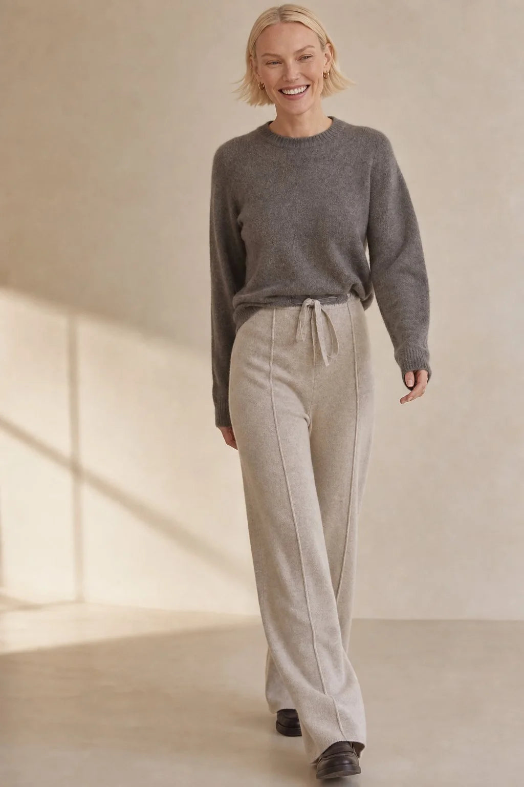 Close-up view of high waist wool trousers showing adjustable drawstring and pintuck detail