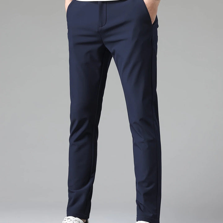 Men's navy trousers styled for business-casual wear with white t-shirt and trainers