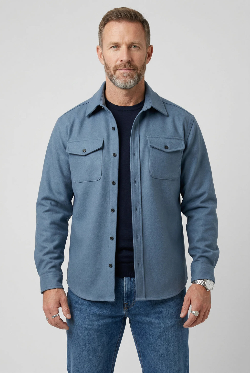 Men's overshirt jacket in light blue with button-up front and chest pockets, worn over navy tee
