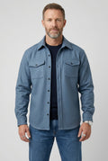 Men's overshirt jacket in light blue with button-up front and chest pockets, worn over navy tee