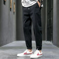 Close-up of men's tapered joggers showing smooth woven fabric and structured tapered leg silhouette