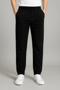 Men's joggers in black with elastic waistband and relaxed straight-leg fit worn with white trainers