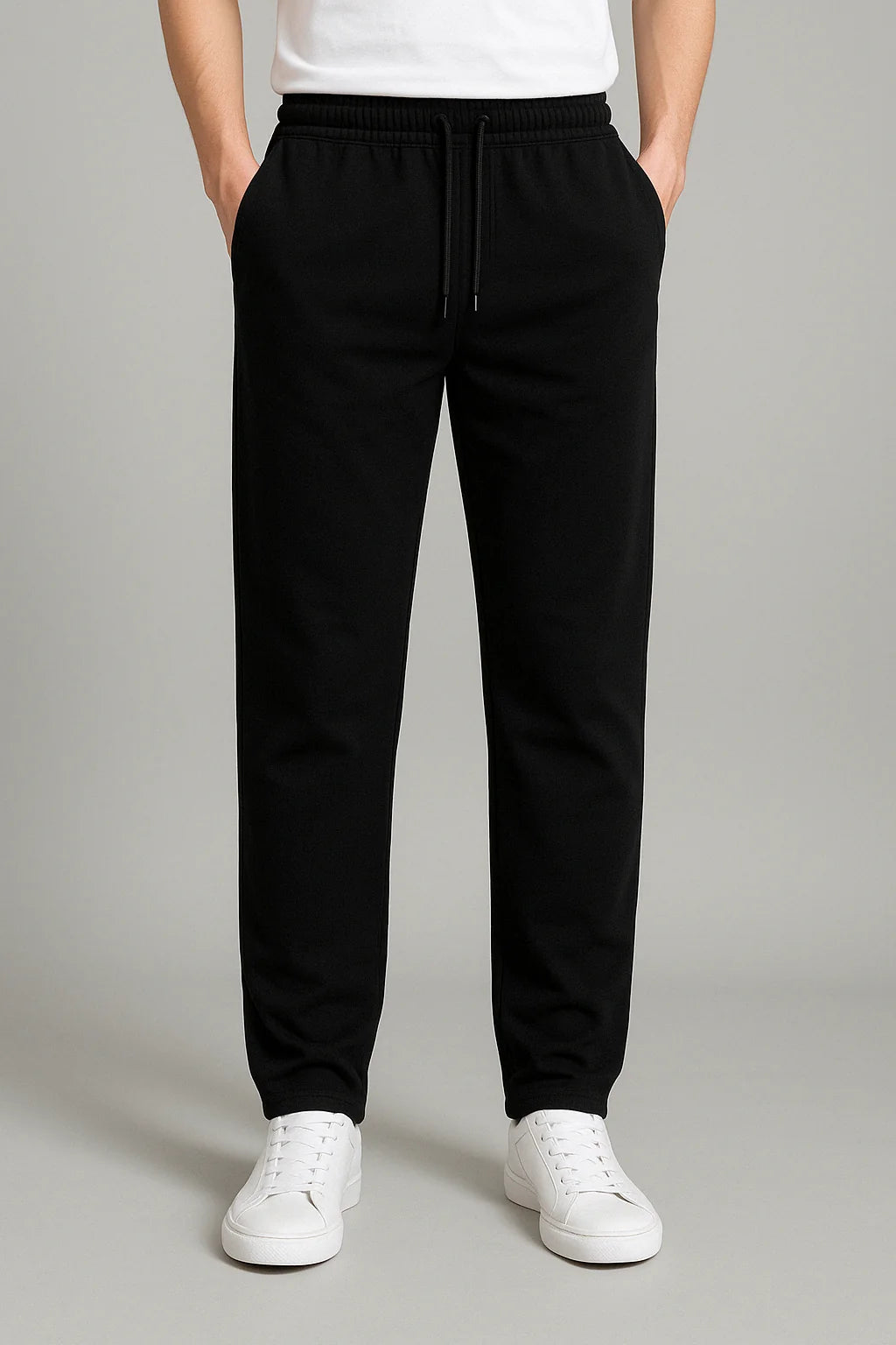 Men's joggers in black with elastic waistband and relaxed straight-leg fit worn with white trainers