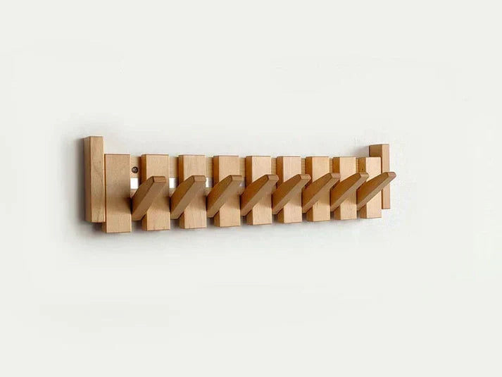 Wooden coat rack with alternating beech and walnut hooks creating piano key visual effect on wall