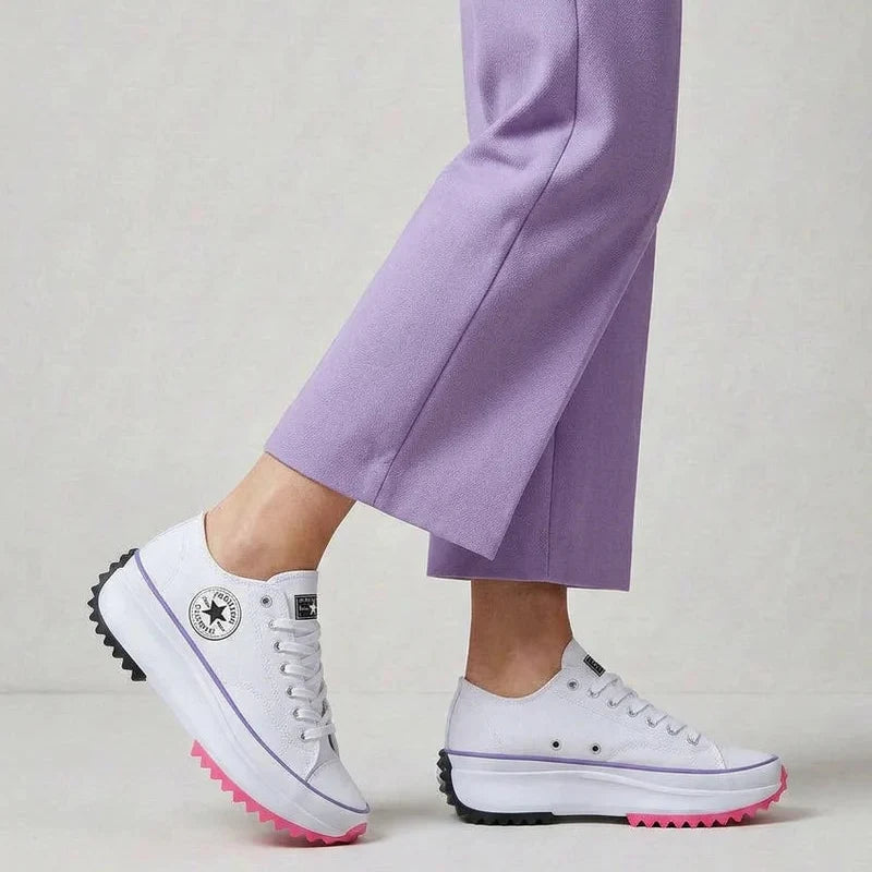 Women's canvas platform trainers in white with chunky sole and lace-up closure worn with lilac trousers