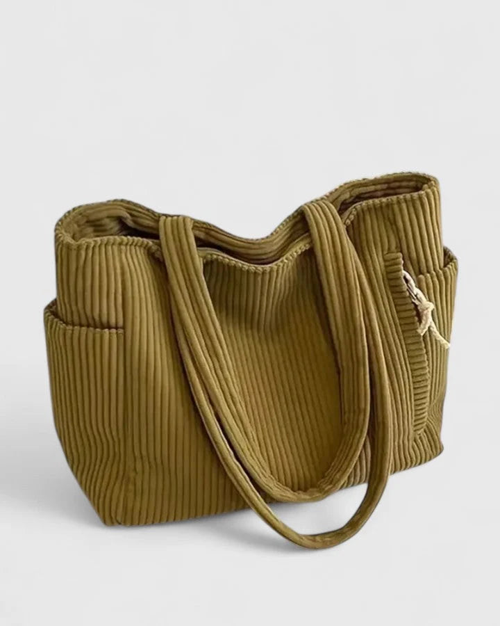 Side view of women's corduroy tote bag displaying exterior pocket with rope detail