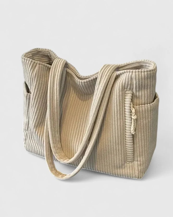 Model carrying spacious corduroy tote bag with dual shoulder straps in casual setting