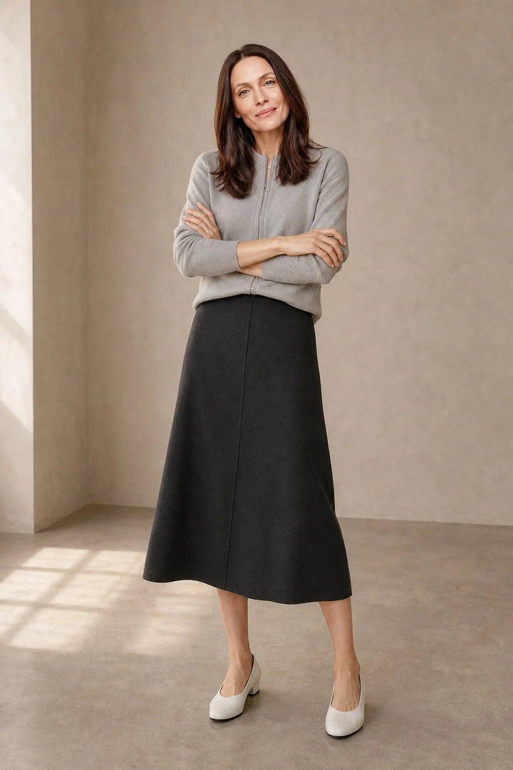 Full-length view of women's wool skirt in olive paired with neutral knitwear for autumn styling