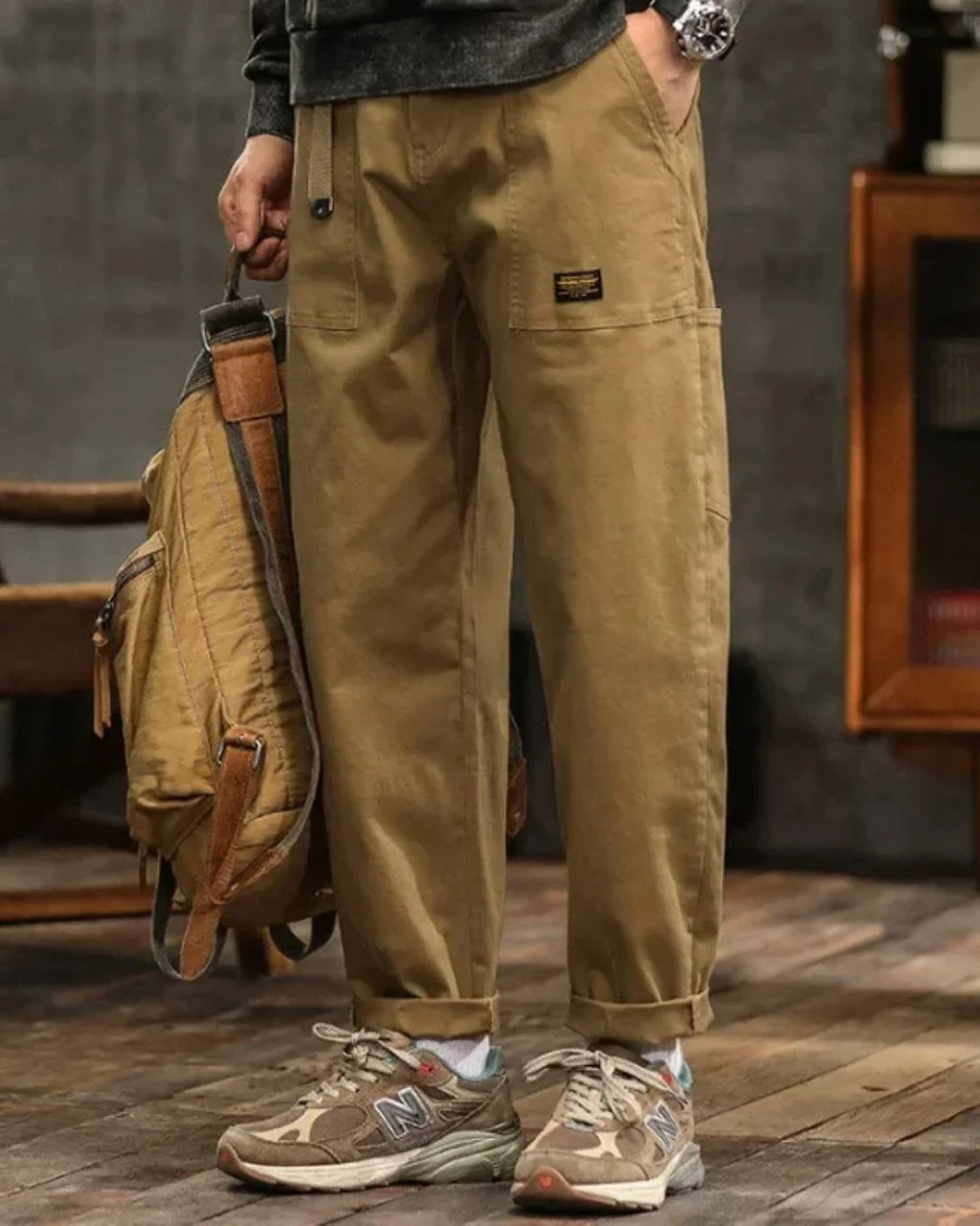 Close-up of cargo trouser waist with pleated detail and structured fabric finish