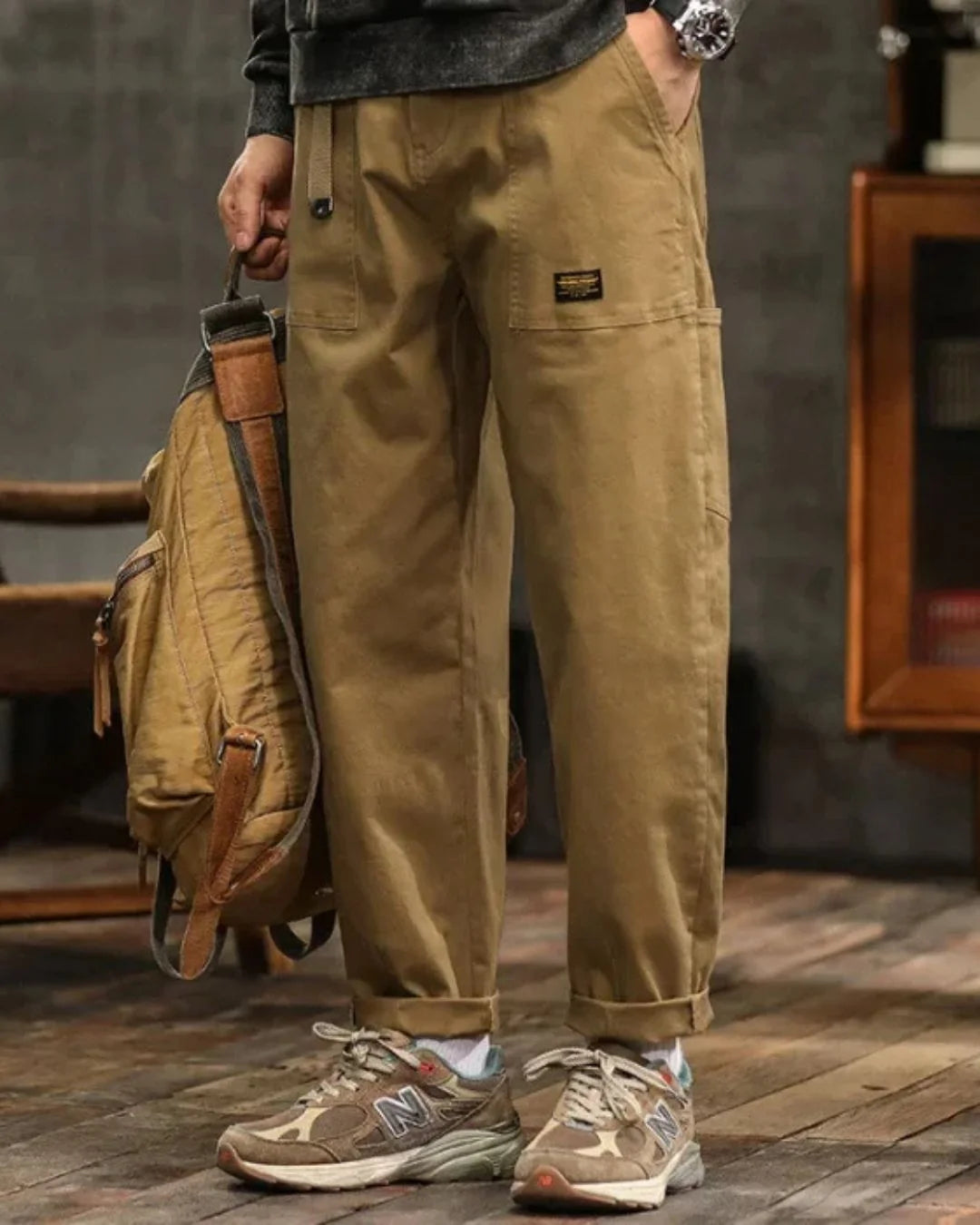 Close-up of cargo trouser waist with pleated detail and structured fabric finish