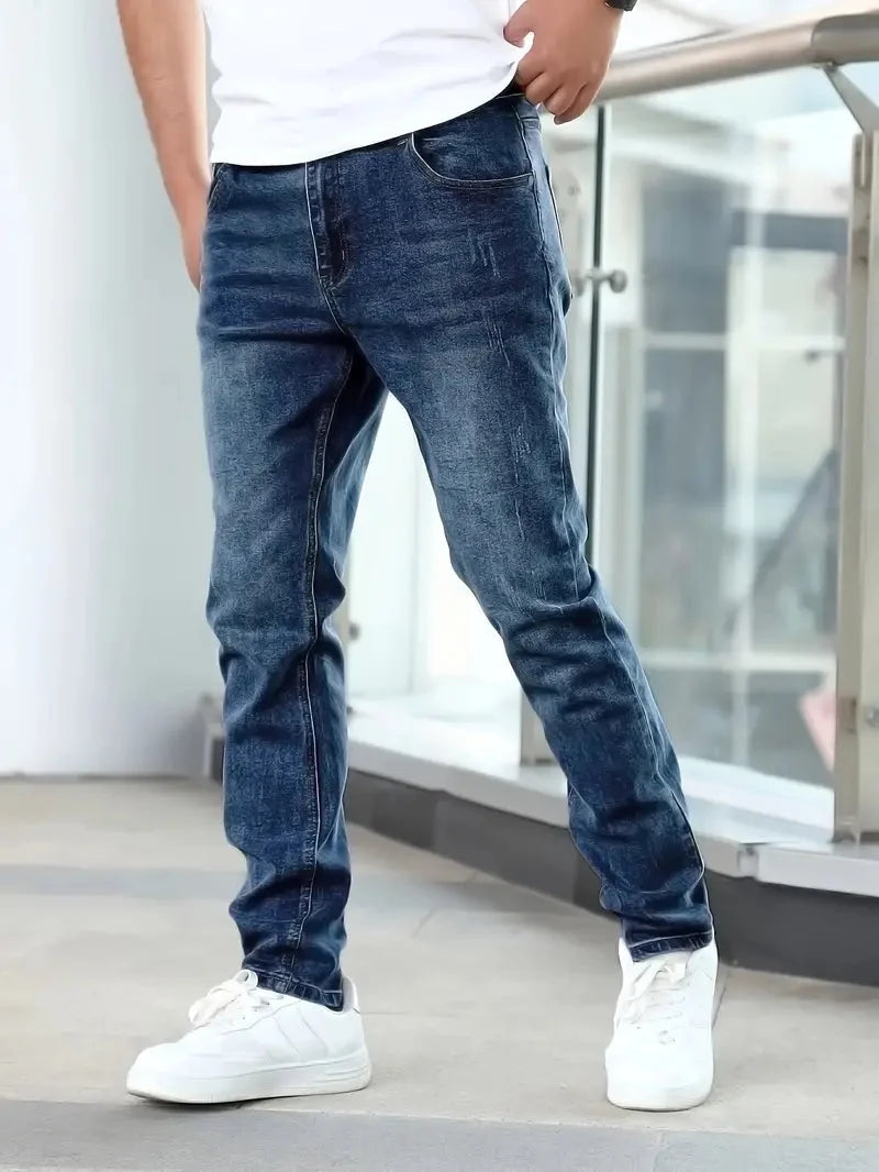 Men's slim fit jeans in medium wash denim with tapered leg and five-pocket styling worn with white trainers