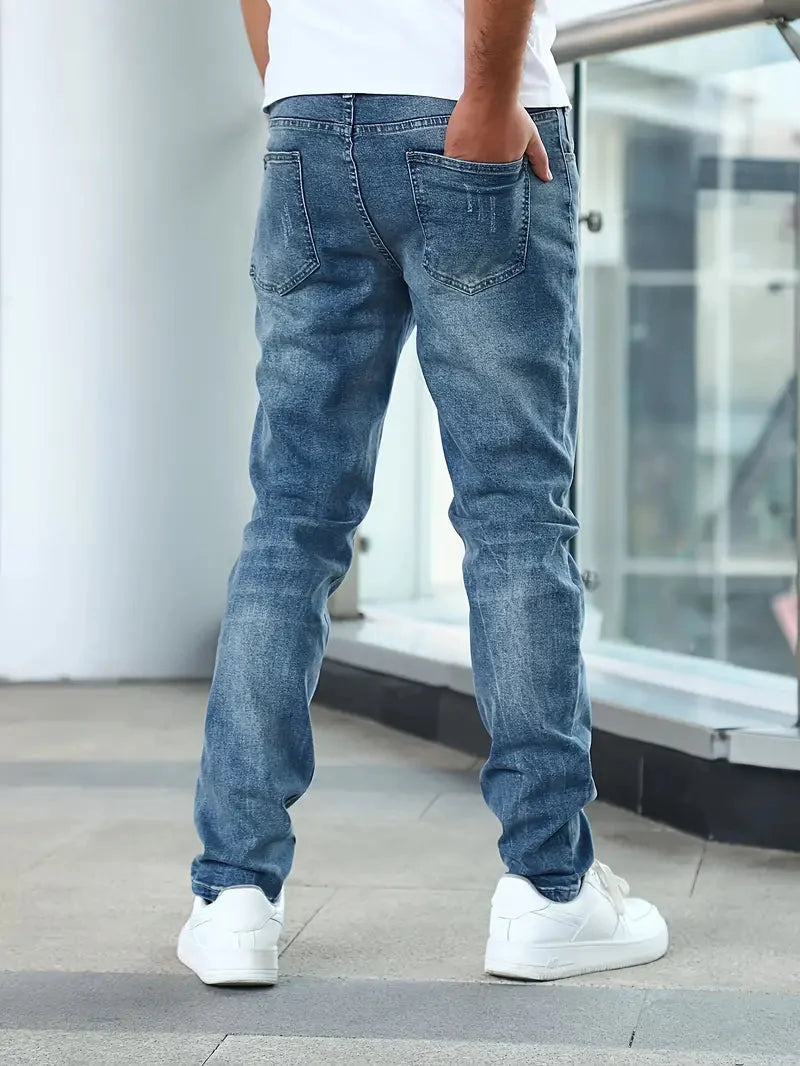 Full-length view of men's medium wash jeans with tapered leg opening and contemporary fit