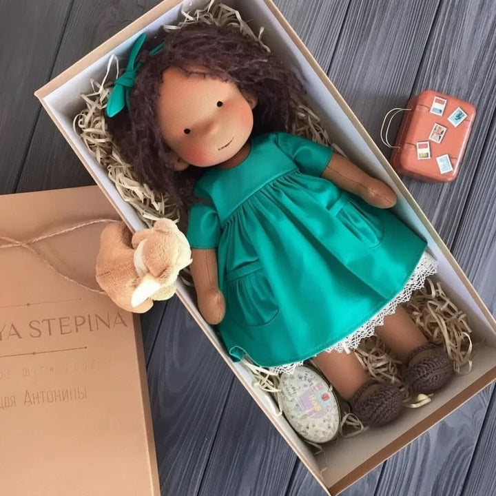 Soft body Waldorf doll with blonde hair resting in natural fibre packaging
