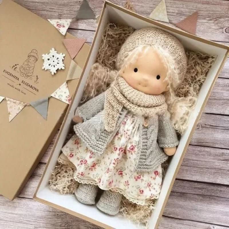 Handcrafted cloth doll with gentle features dressed in coordinating knitted outfit and bonnet