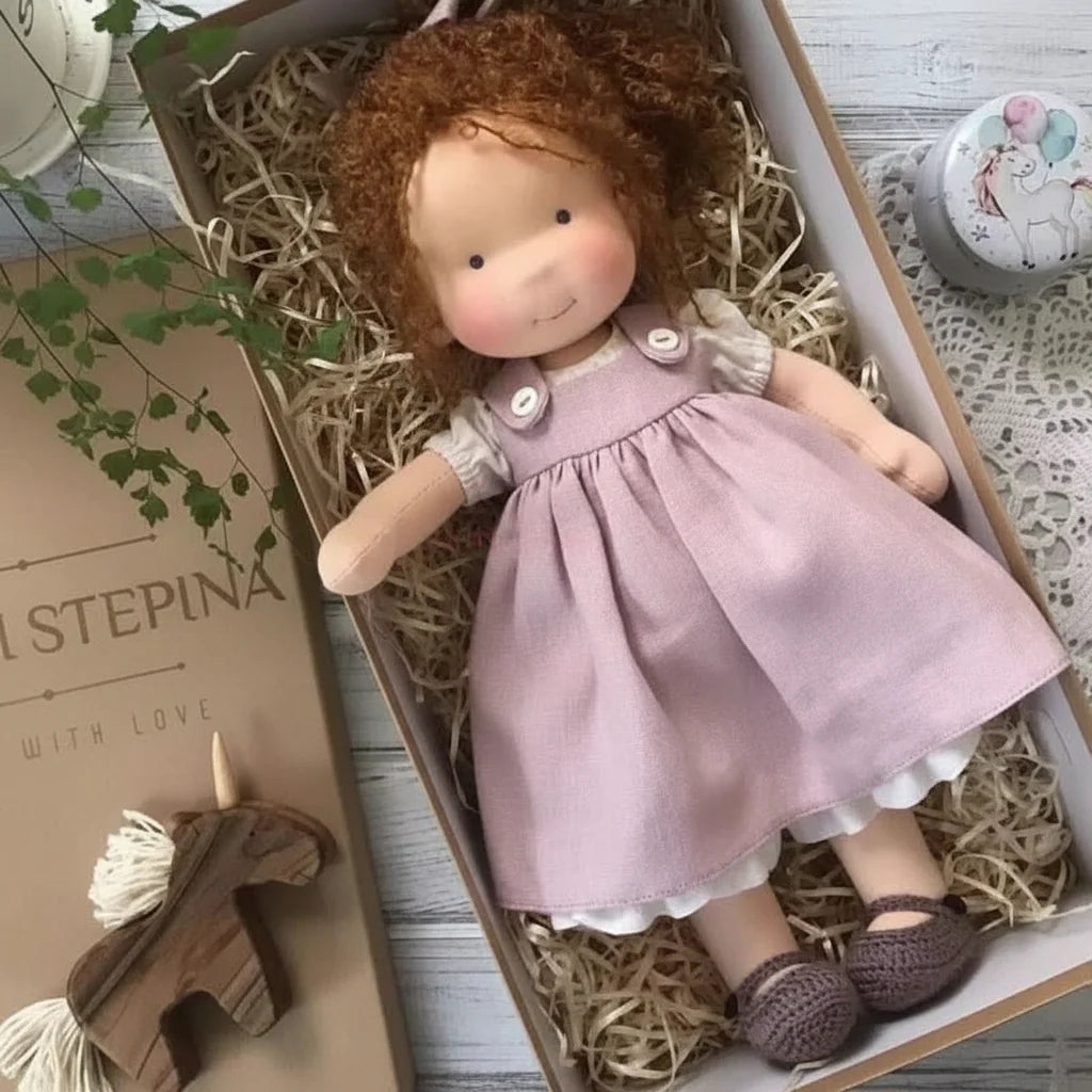 Close-up of cloth doll wearing cream knitted booties and lilac dress with lace trim