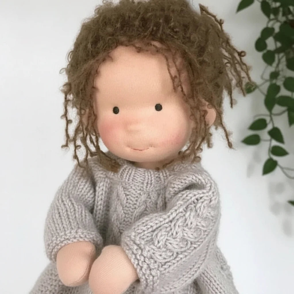 Soft body doll dressed in cream cardigan and lilac dress encouraging imaginative play