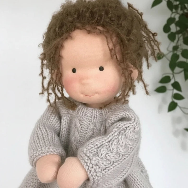 Soft body doll dressed in cream cardigan and lilac dress encouraging imaginative play