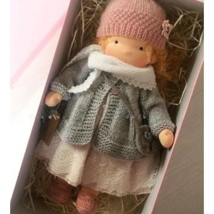 Handcrafted Waldorf doll with simple facial features and coordinating knitted garments