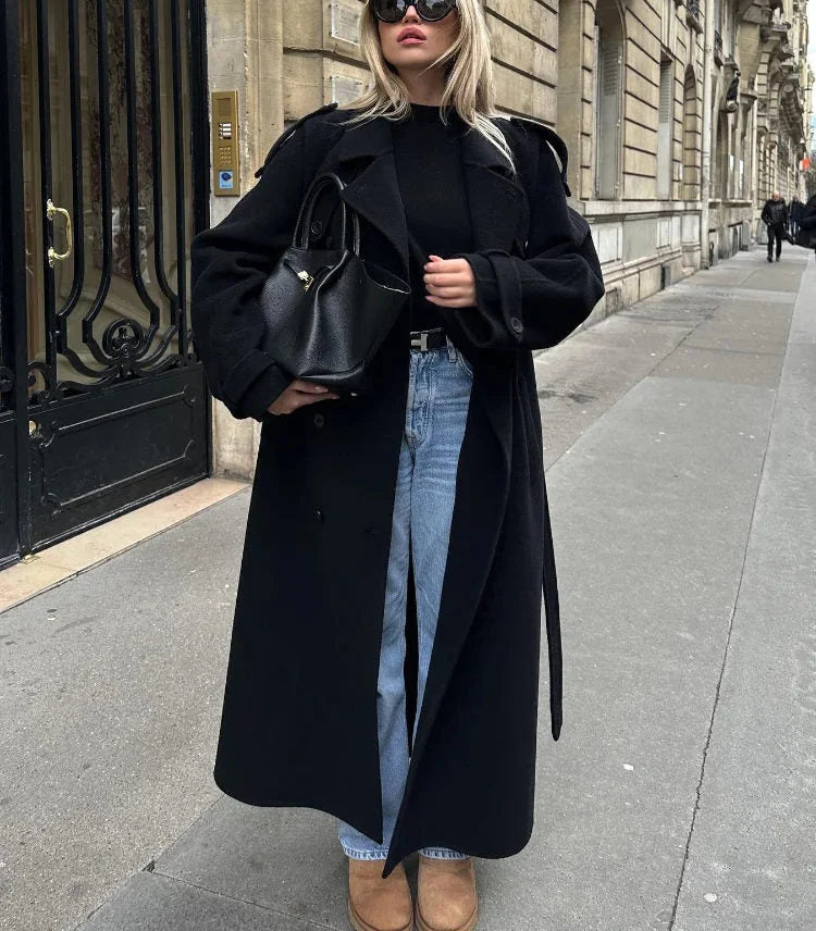 Long black trench coat styled with jeans and ankle boots for casual autumn look