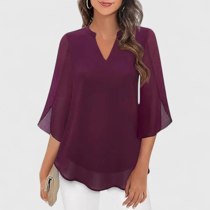 Flat lay of V-neck blouse highlighting flared sleeve shape and drape