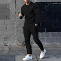 Men's casual two-piece set in black with crew neck top and tapered trousers worn outdoors