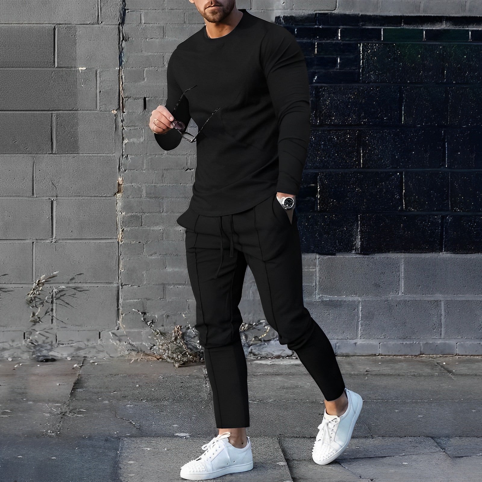 Men's casual two-piece set in black with crew neck top and tapered trousers worn outdoors